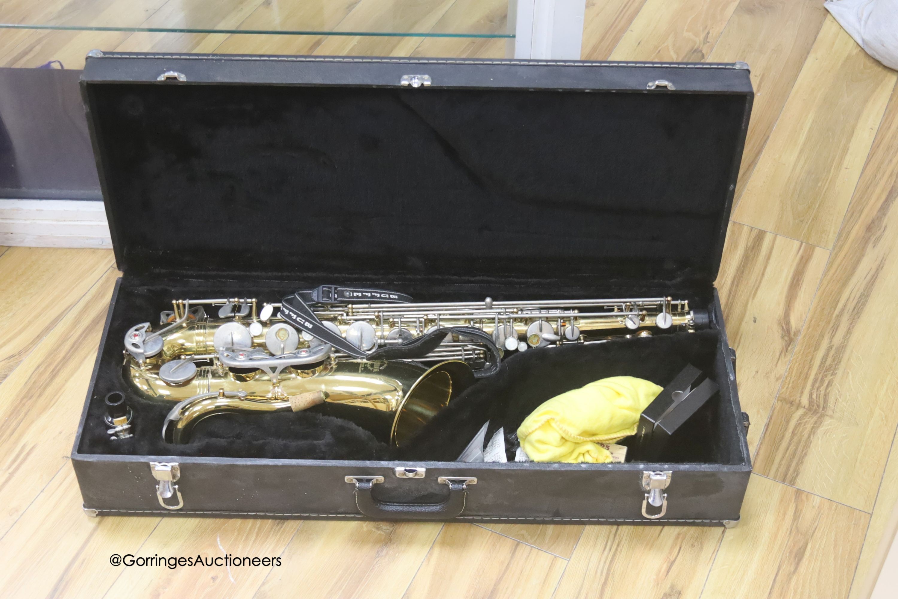 A cased Earlham brass saxophone and music sheets